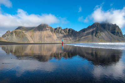 Person standing on beach against mountain
