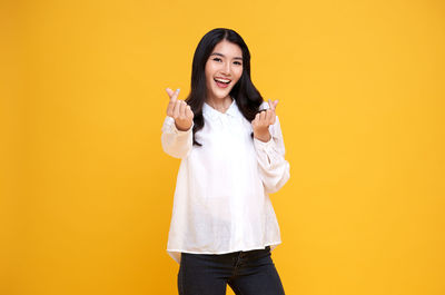 Portrait of a smiling young woman against yellow background
