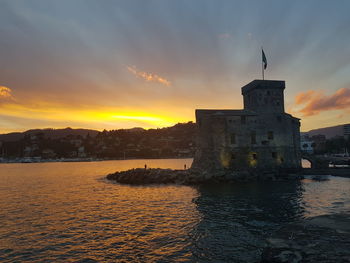 Castle by sea during sunset