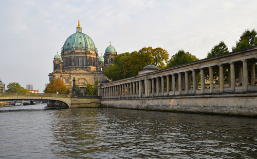 View of temple by river against sky