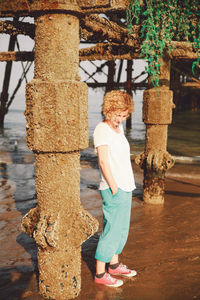 Full length of woman standing by column on sunny day