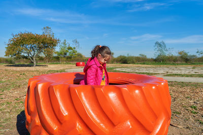 Young girl playing on a brightly colored tractor wheel at a farm fair on halloween