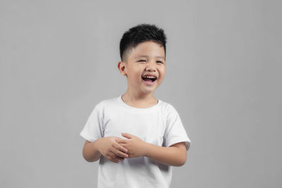 Portrait of smiling boy standing against white background