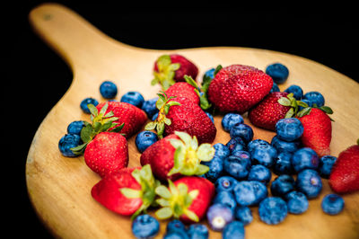 Closed up of strawberries and blueberry on wooden table with black background 