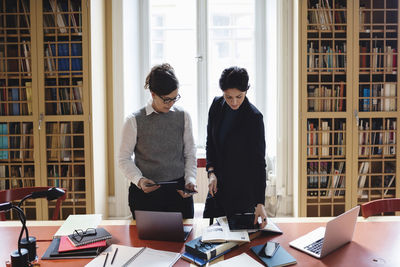 High angle view of female lawyers using technologies at table in library