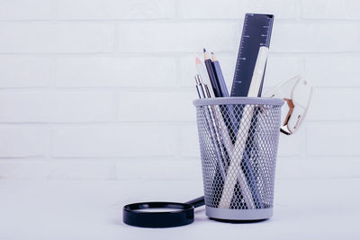 Close-up of pen on table against white wall