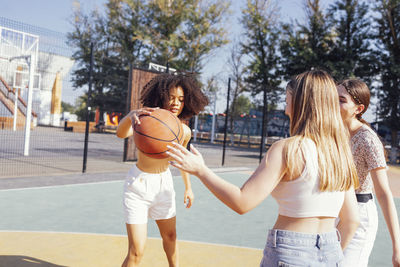 Rear view of woman playing basketball in court