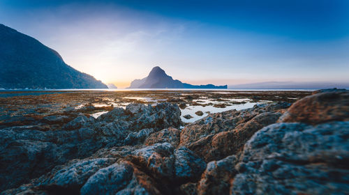 Rocks on beach against blue sky