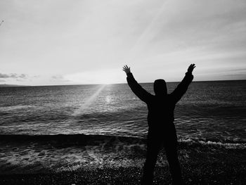 Silhouette man standing at beach against sky