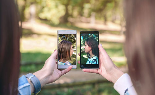 Female friends talking selfie with smart phones at park