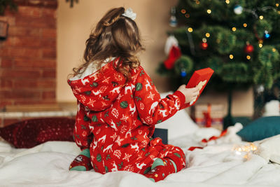 Little girl opens a christmas present near the christmas tree