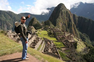 Side view of man standing on mountain against sky