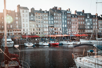 Sailboats moored on canal by buildings in city against sky