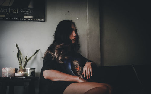Woman looking away while sitting on chair at home