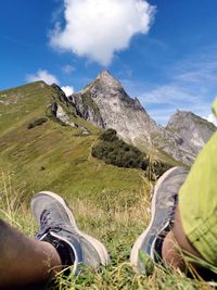 Low section of person on mountain against sky