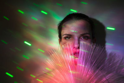 Portrait of beautiful woman standing against illuminated light