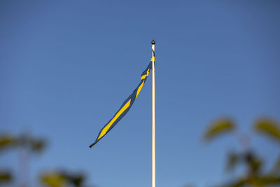 Low angle view of bird flying against clear blue sky