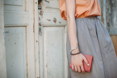 Side view of woman holding book while standing by door