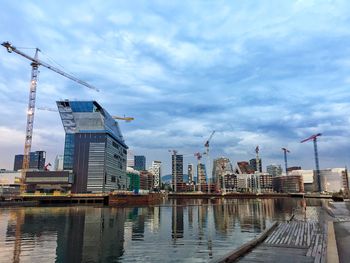 Buildings by river against sky in city