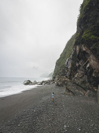 View of calm beach against cloudy sky