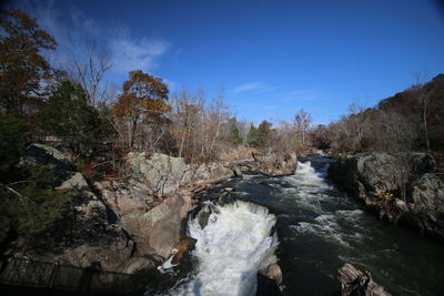 Scenic view of waterfall in forest against sky