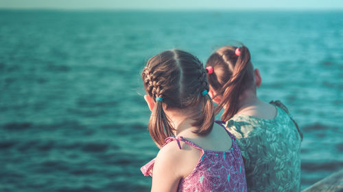 Rear view of women standing against sea