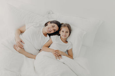 High angle view of mother and daughter lying on bed