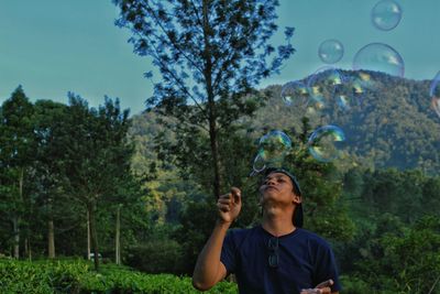 Mid adult man blowing bubbles at park