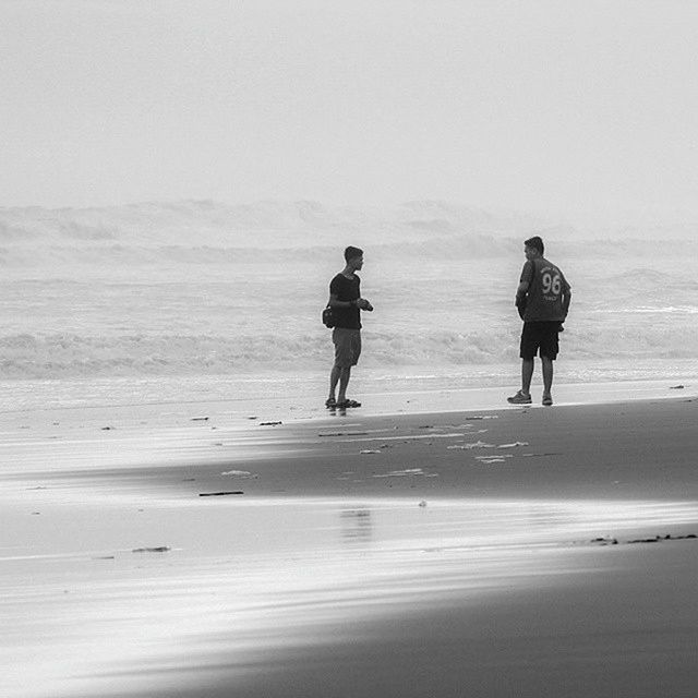 beach, sea, sand, full length, shore, horizon over water, rear view, walking, lifestyles, water, leisure activity, standing, clear sky, vacations, men, tranquil scene, tranquility, sky