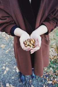 Low section of woman wearing jacket while holding seeds outdoors