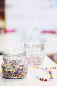 Jars full of beads with necklaces on table in kindergarten