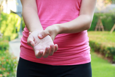 Midsection of woman holding hand while standing on field