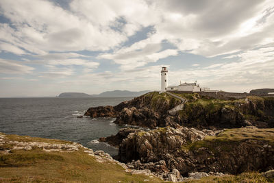 Fanad lighthouse amidst sea and buildings against sky