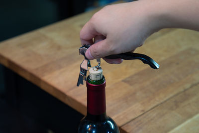 Close-up of hand holding wine bottle on table