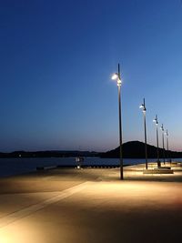 Street light by sea against clear blue sky