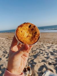 Close-up of hand holding ice cream on beach