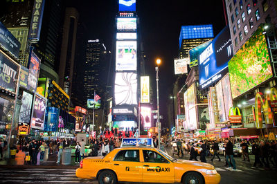 Taxi and crowd on city street at night