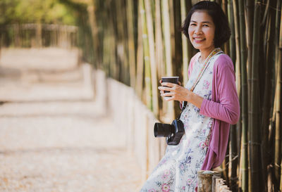 Young woman using mobile phone while standing on staircase