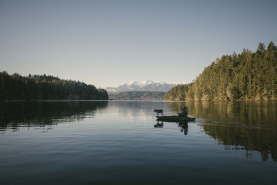 Mid distance view of man in boat on lake against sky