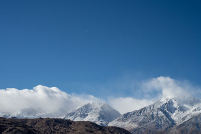 Scenic view of snowcapped mountains against blue sky