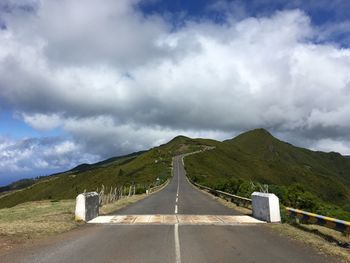 Road leading towards mountains against sky