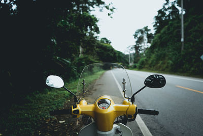 Motor scooter parked on roadside against trees