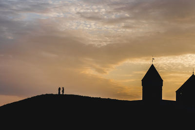 Silhouette temple against building during sunset