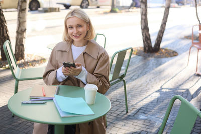 Young woman using mobile phone while sitting on table