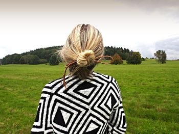 Rear view of woman on grassy field against sky