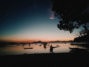 Silhouette people on beach against sky at night