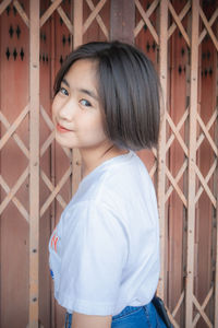 Portrait of smiling girl against closed gate