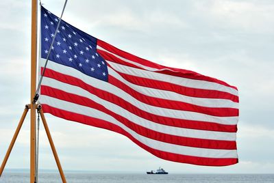 Close-up of flag by sea against sky