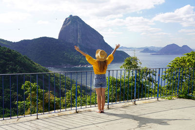 Girl raising arms looking cable cars climbs from urca hill to sugarloaf mountain, rio de janeiro