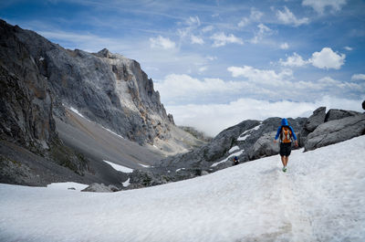 Rear view of man on snowcapped mountain against sky